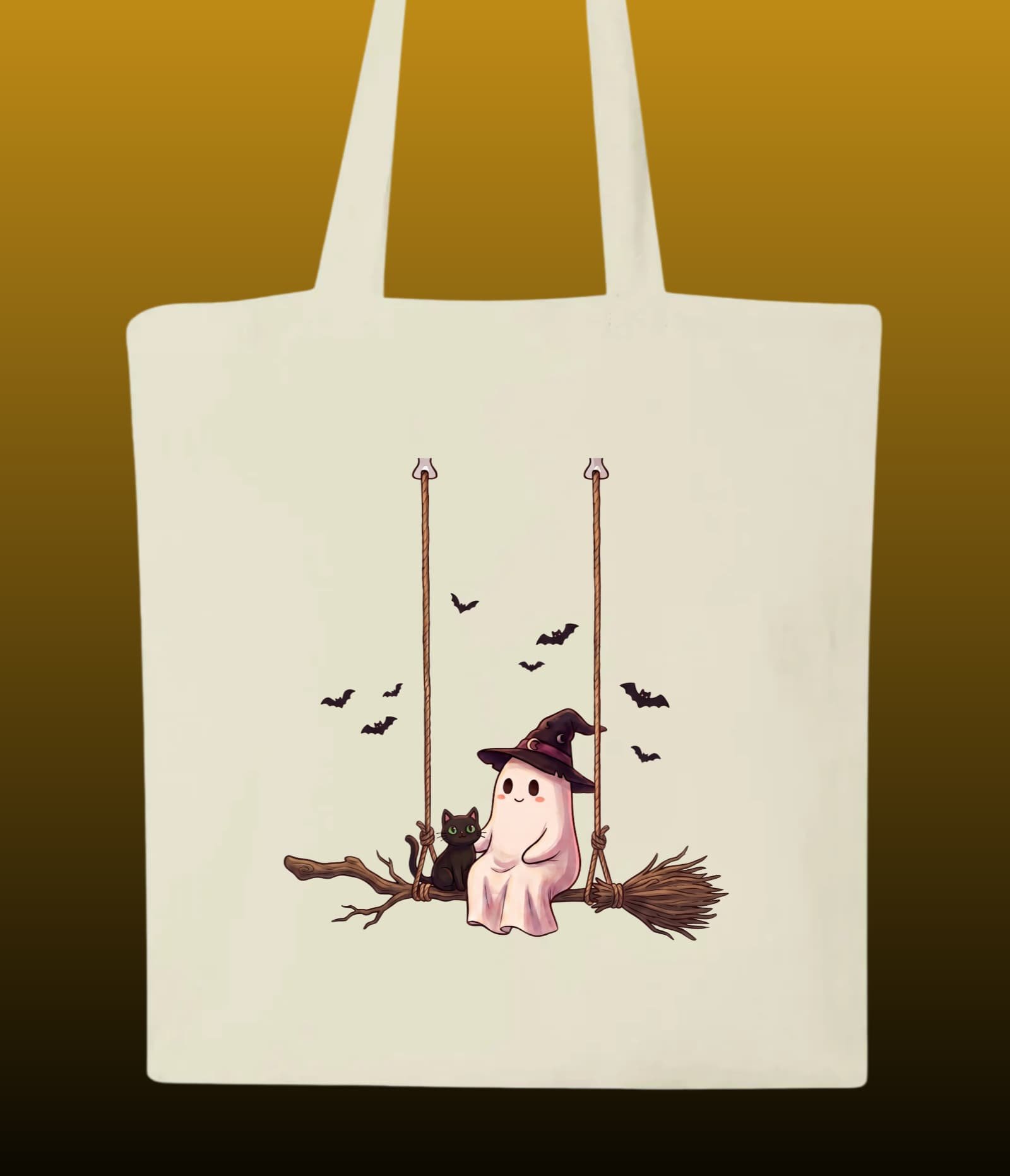 Tote bag écru en tissu recyclé illustré d'un fantôme portant un chapeau de sorcière assis sur un balai balançoire avec un chat noir